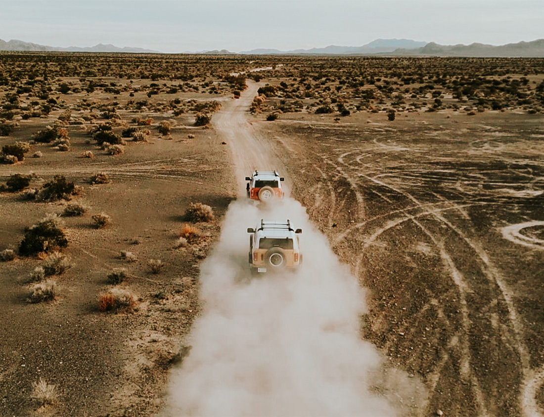 A cinematic view of broncos driving down a dirt road.